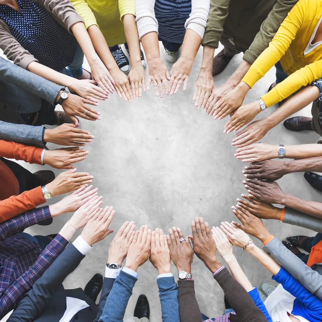 Overhead view of many hands forming a circle.