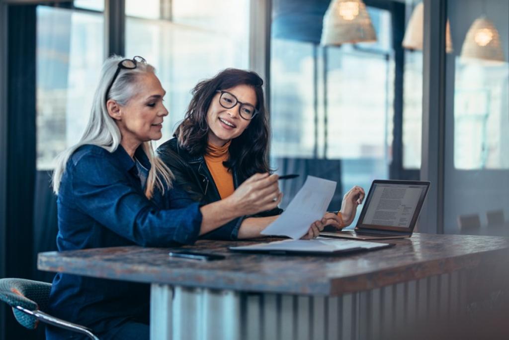 Two women sitting at a table reviewing a paper