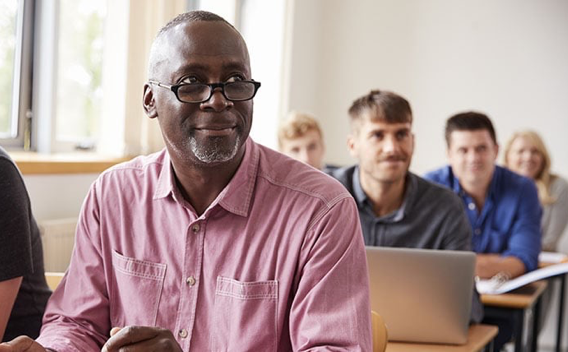 Older man sitting in front of class mixed in with other younger students