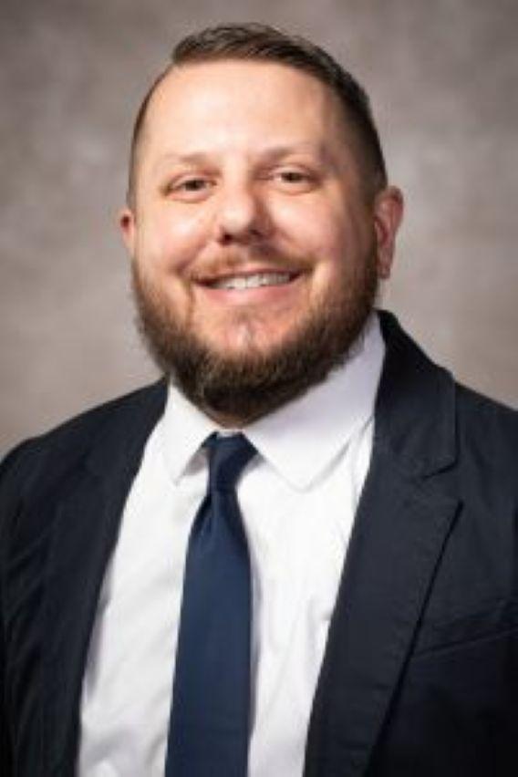 Smiling man in beard and dark suit with white shirt. 