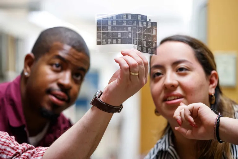 Two students studying a slide in the library
