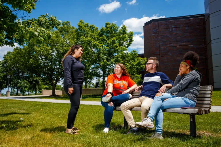 A group of people sitting on a bench and talking outside