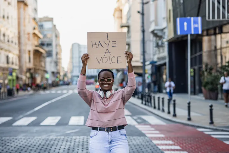 Person holding a sign saying "I have a voice"