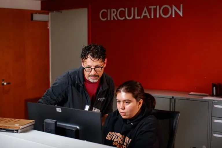 A staff member helping a student working in the library