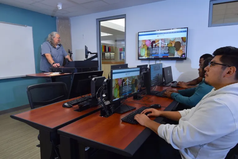 Instructor and Students working on computers in a computer lab. 