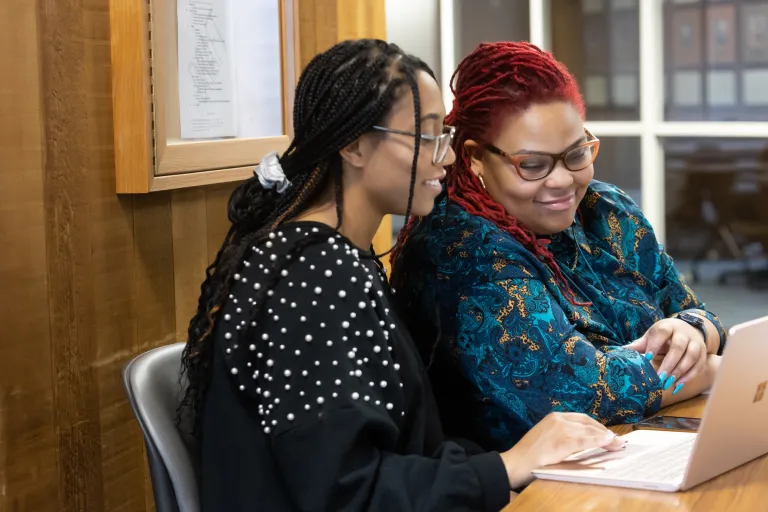 Two social work students look at a laptop