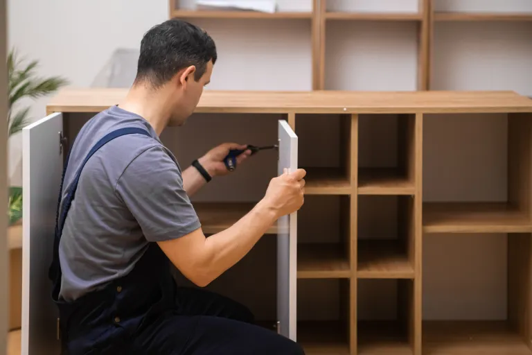Carpenter assembling door to cabinet.