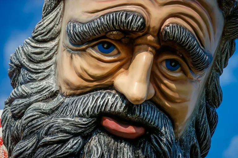 Colorful statue of an old man's face with blue eyes and a gray beard.