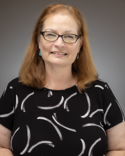 Woman with red hair and glasses, in black and white shirt