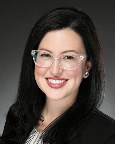 Woman in glasses with long black hair, in stripped shirt and black jacket