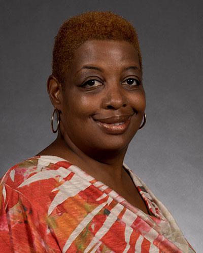 Woman with short reddish-brown hair, wearing multi-color shirt