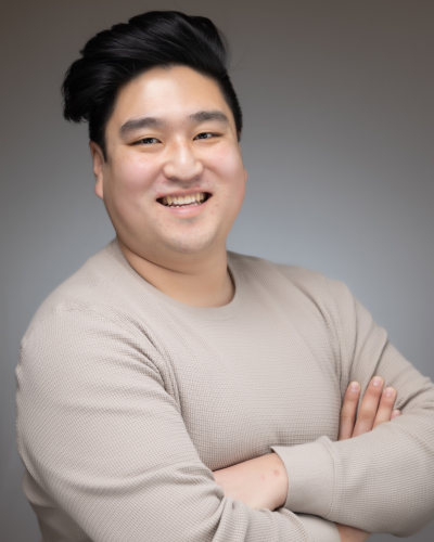 Man with black hair, wearing tan sweater, professional headshot