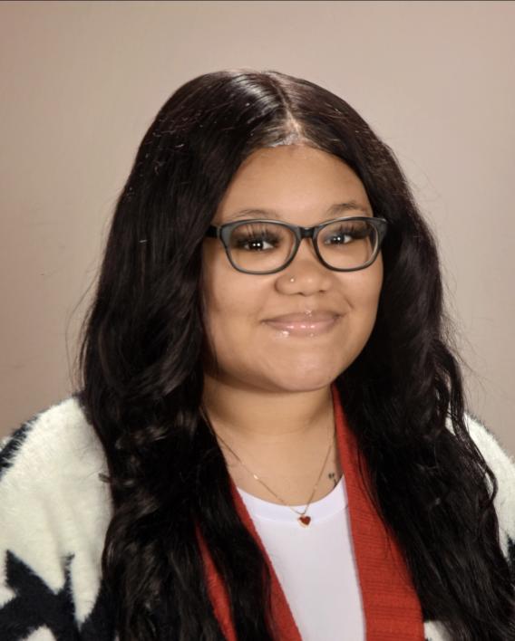Professional headshot, woman with black hair and glasses, wearing white shirt and colorful sweater