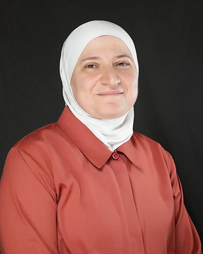 Professional headshot of woman in white haijb, wearing coral shirt