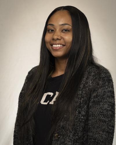 Woman with long black hair, wearing black and white shirt and sweater