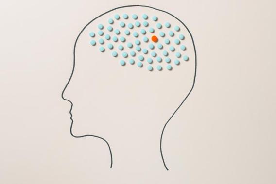 Graphic: Human head outline filled with many blue circles and one orange circle.