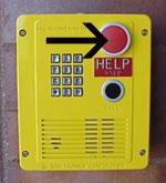 Yellow emergency call box with keypad, red HELP button, and black arrow pointing to it.