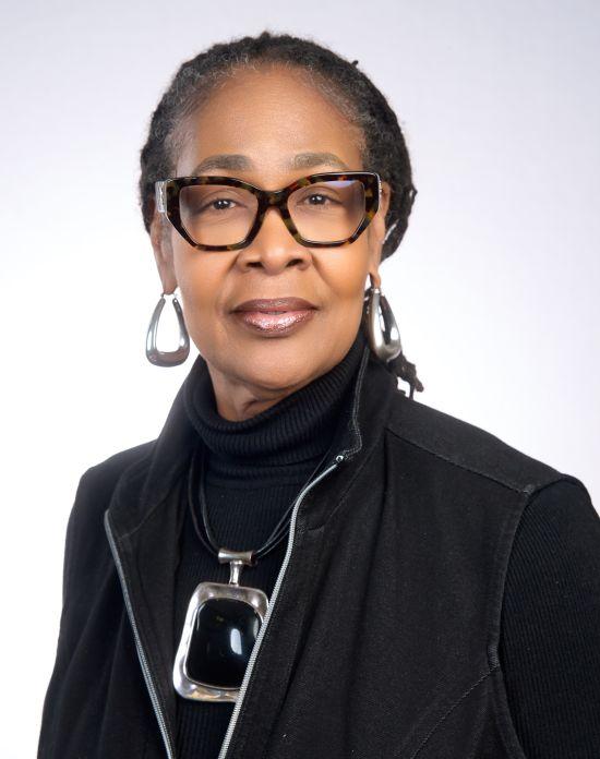Woman in glasses, black shirt and jacket, with silver jewelry