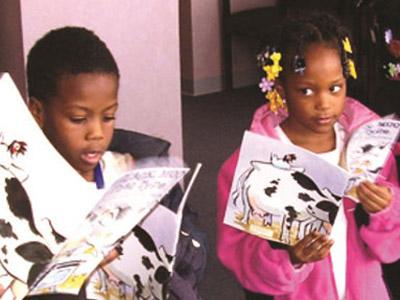 Two kids reading books with cow illustrations