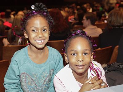 Two kids smiling in an audience