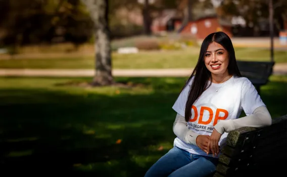 Student smiling and sitting on a bench