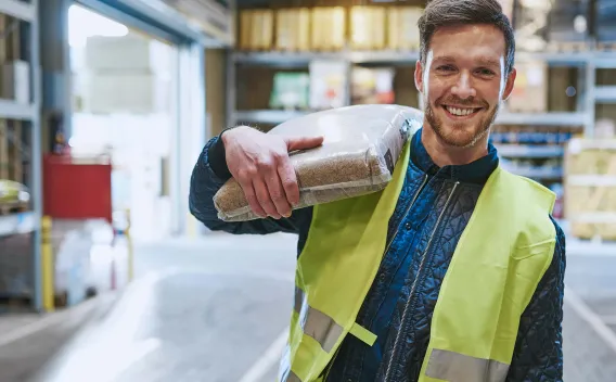 Man holding bag of mulch inside warehouse