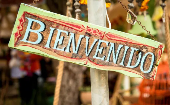 Wooden "Bienvenido" sign hanging on pole