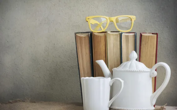 Glasses on top of books and tea pot with mug
