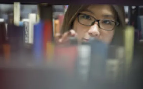Student looking at books on shelf