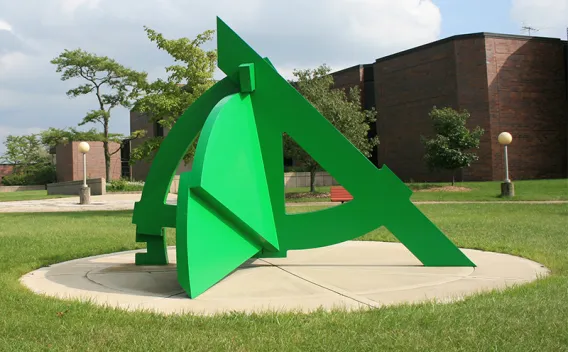Gray and black angled ramp with colorful supports, on wood chips and grass.