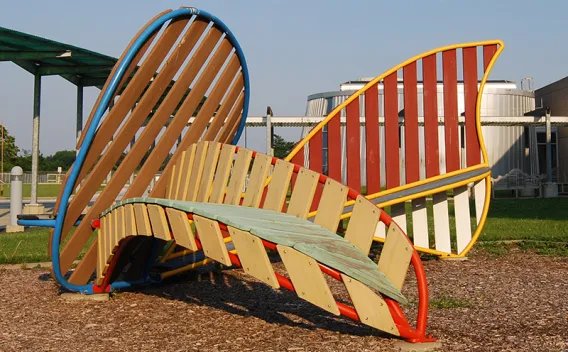Colorful, modern outdoor sculpture with slatted wood and metal, including a curved bench.