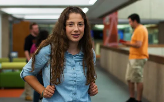 A young freshman woman walking in the library