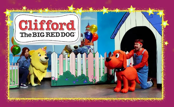 Photograph: Clifford The Big Red Dog stage show with red dog, yellow dog, actors, fence, and doghouse.