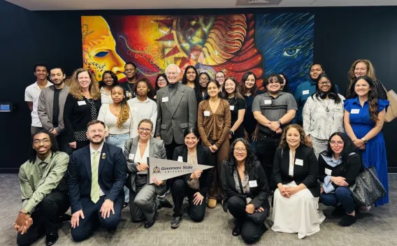 A group of people smiling in front of a vibrant mural