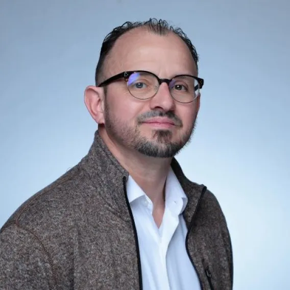Man in glasses, beard, white shirt, and grey jacket