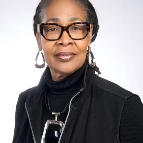 Woman in glasses, black shirt and jacket, and silver jewelry