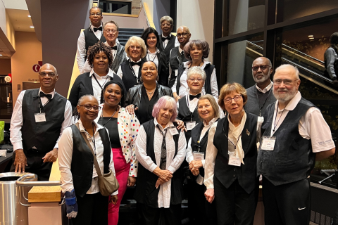 Group of venue staff and volunteers posing together in uniform inside the building.