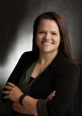 Professional headshot of a smiling woman with dark hair.
